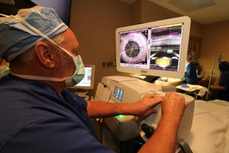 A surgeon is using an electronic device to examine the eye.