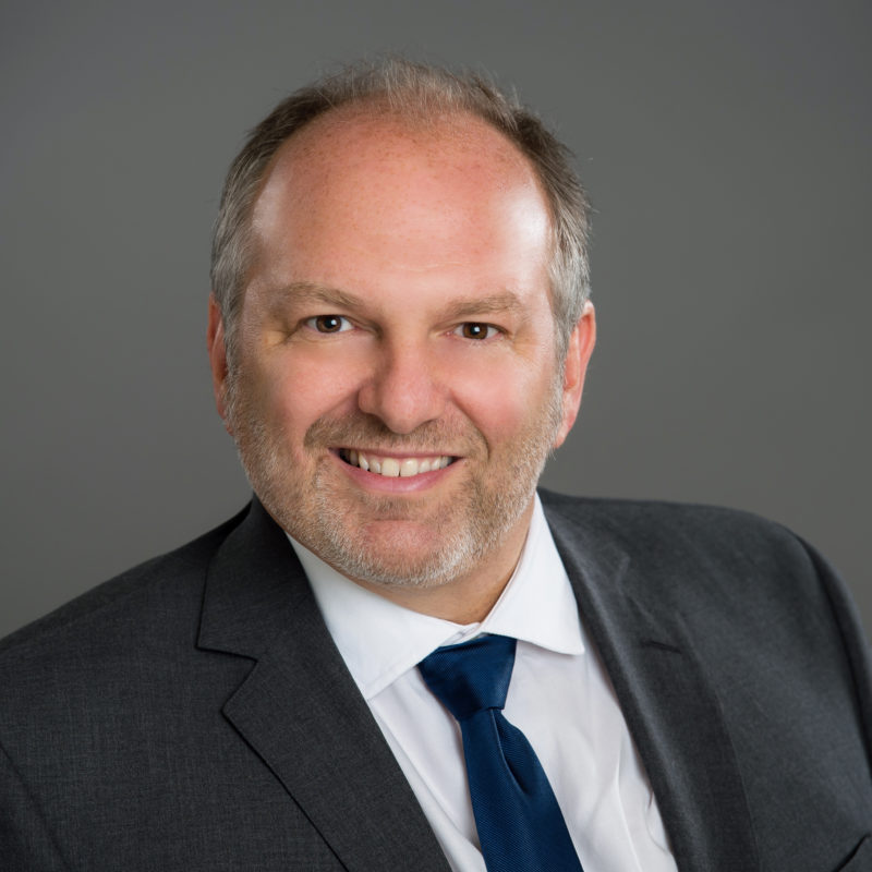 A man in suit and tie smiling for the camera.