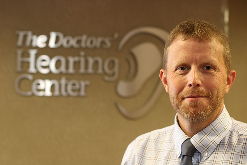 A man standing in front of the doctors ' hearing center sign.