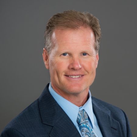 A man in suit and tie smiling for the camera.